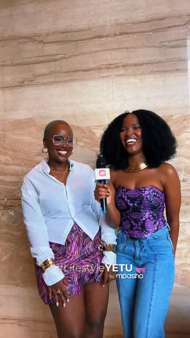 Two women in a microphone interview against a marble wall